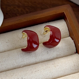 Macro detail of retro C-shaped earrings with dark red enamel and gold plating
