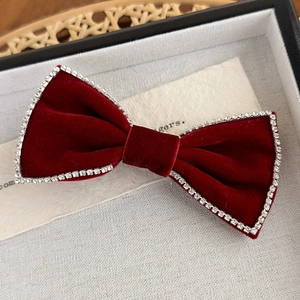 Close-up of a red velvet bow hair clip with sparkling rhinestone edges and retro style