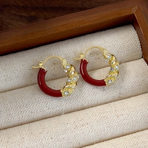 Close-up of retro gold-tone hoop earrings with red enamel and sparkling crystals