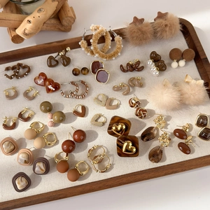 Dettaglio di orecchini geometrici marroni in stile vintage su un vassoio beige