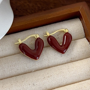 Detail of red enamel heart earrings with gold metal clasp on a jewelry display box
