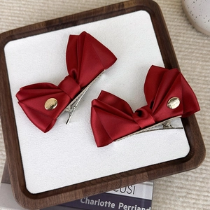 Lot de deux barrettes nœuds en satin rouge avec médaillons dorés sur fond décoratif