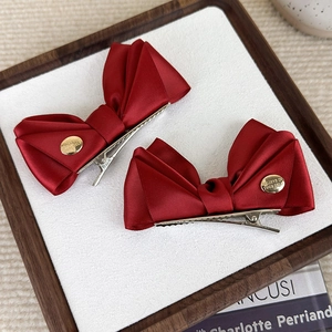 Détail de barrettes noeuds en satin rouge avec médaillons dorés gravés de texte inspirant