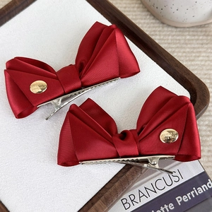 Barrettes nœuds en satin rouge élégantes avec boucle dorée sur fond vintage chic