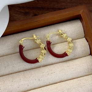 Macro shot of retro gold-tone heart earrings with deep red enamel in a jewelry tray