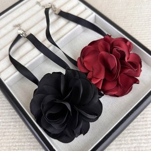 Detail view of large satin rose chokers with adjustable metal lobster clasps in a jewelry box
