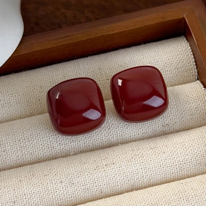 Macro shot of retro red square stud earrings with high-gloss finish in a jewelry box