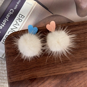 Gros plan détaillé des boucles d'oreilles en fourrure blanche et coeurs bleu et rose