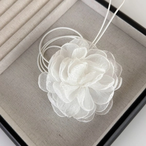 Gros plan d'un choker camélia en tissu blanc avec de délicats pétales de tulle multicouches