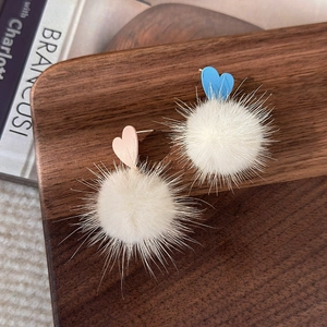 Détails de boucles d'oreilles d'hiver avec cœurs rose et bleu et pompons blancs