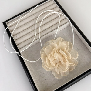 Vue détaillée de la fleur de camélia en organza beige avec cordon minimaliste