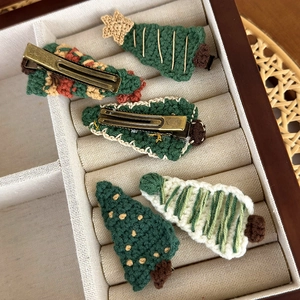 Dettaglio di cinque fermagli per capelli a forma di albero di Natale fatti a mano all'uncinetto