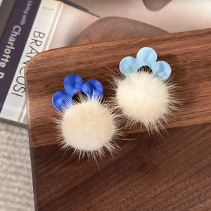 Détail de boucles d'oreilles fleurs en peluche hivernales sur plateau bois