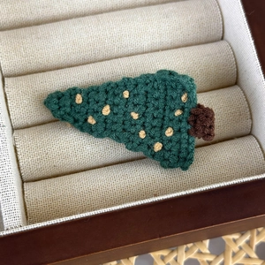 Dettaglio del fermaglio per capelli a forma di albero di Natale fatto all'uncinetto