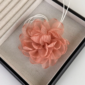 Gros plan d'un camélia en tissu pêche fait main avec des pétales de tulle et des cordons