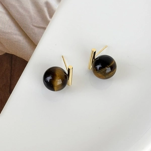 Detailed macro view of tiger eye stud earrings with gold metal bars and natural brown stripes