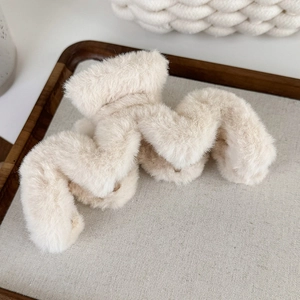 Détail macro d'une pince à cheveux pelucheuse ondulée en fausse fourrure blanc crème