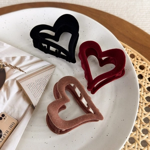 Elegant heart-shaped flocked hair claws in black, burgundy and brown on a ceramic tray