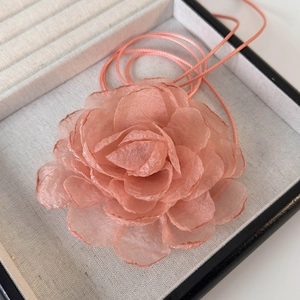 Gros plan détaillé d'un tour de cou camélia en tissu 3D rose tendre avec rubans soyeux