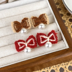 Close-up of knit bow earrings with white pearls in red and brown colors for a retro look