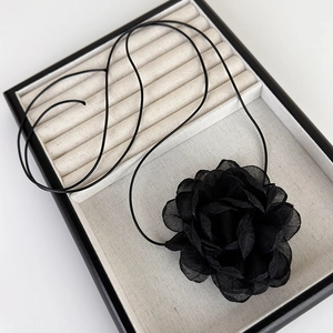 Détail du ras-du-cou camélia 3D en tissu noir avec pétales en mousseline et cordon ciré