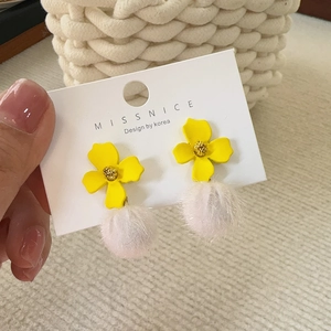 Detail of yellow flower earrings with white pom-poms and gold bead center accents