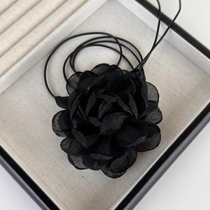 Détail d'un grand collier choker camélia 3D en résille noire avec rubans et pompons