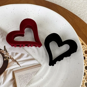 Detail view of red and black velvet heart hair claws on a ceramic plate for styling