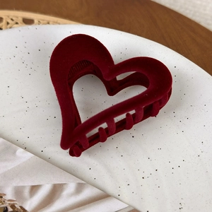 Detail shot of vintage dark red velvet heart-shaped hair claw clip on a white plate