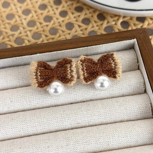 Detail of knitted bow stud earrings with white pearls on a vintage jewelry display