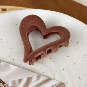 Close-up of velvet-flocked heart hair claw clip in caramel brown on a ceramic plate