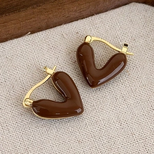 Dettaglio di orecchini a cuore vintage marroni con bordo dorato e texture a olio