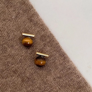Retro tiger eye stud earrings with gold metal bar on brown knit fabric background