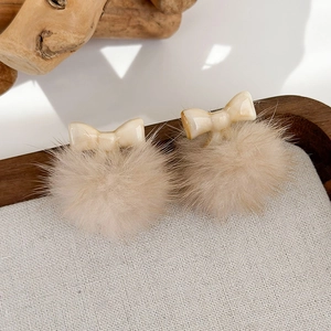 Dettaglio di accessori per capelli con pompon e fiocco su un vassoio di legno rustico