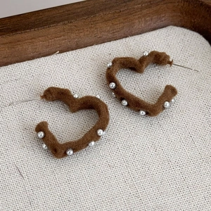 Dettaglio di orecchini a cuore in velluto marrone con piccole decorazioni in argento