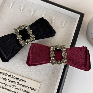 Velvet bow hair clips in black and burgundy with crystal buckles on a jewelry display box