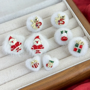 Plush Santa and reindeer earrings with red enamel charms on a beige jewelry display