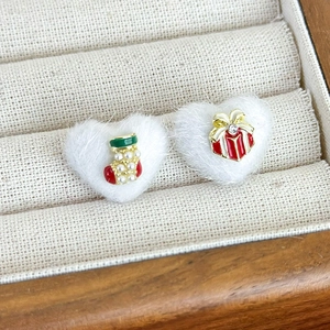 Detail of Santa sock and gift box stud earrings on white plush heart backings