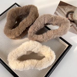 Trois pinces à cheveux en peluche douce de couleur marron, café et beige sur un plateau