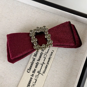 Close-up of a burgundy velvet bow hair clip with a luxury crystal buckle for women