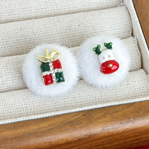 Close-up of asymmetric Christmas stud earrings with plush white balls and reindeer detail
