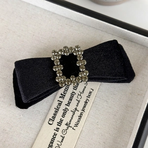 Detail view of black velvet bow hair clip with crystal rhinestone center in a jewelry box