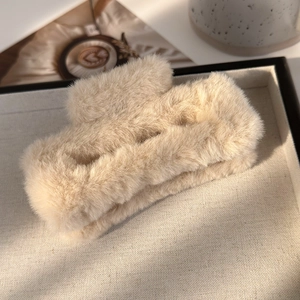 Gros plan d'une grande pince à cheveux carrée en peluche douce de couleur beige