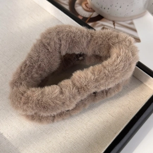 Détail d'une grande pince à cheveux en peluche marron sur un plateau de présentation