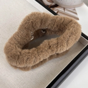 Gros plan détaillé d'une grande pince à cheveux en peluche marron au design ondulé