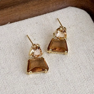 Dettaglio di orecchini geometrici vintage con cristalli ambra e champagne incastonati in oro
