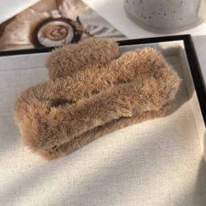 Gros plan d'une grande pince à cheveux en peluche marron dans un plateau élégant