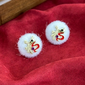 Close-up of white plush Santa ball earrings with golden Fu character and dragon charm