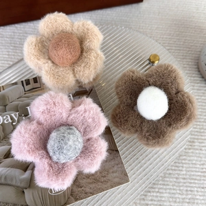 Trois pinces à cheveux fleurs en peluche en beige, rose et brun sur un plateau
