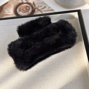 Détail d'une grande pince à cheveux carrée en peluche noire avec texture fausse fourrure